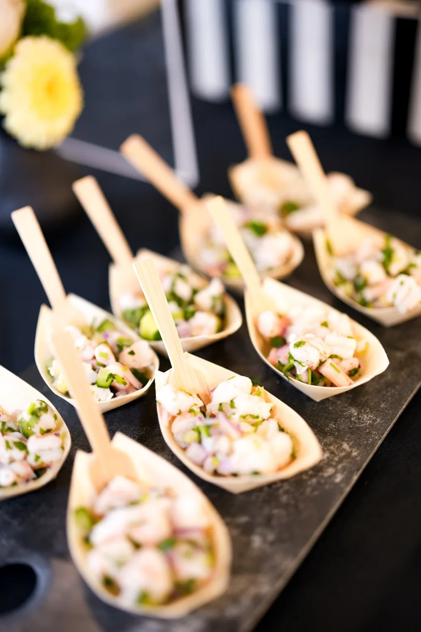 Ceviche served in bamboo cone cups with wooden picks on a dark slate board